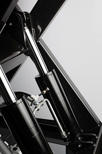 Industrial hydraulic cylinders on black machinery.
